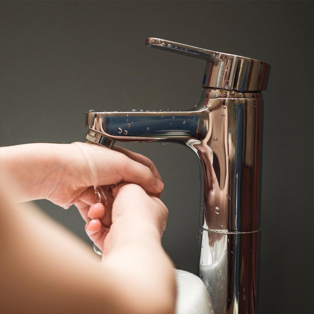 Troisième photo du slider pour la page industrie représentant des mains sous un robinet doré avec un filet d'eau qui coule sur un fond gris foncé